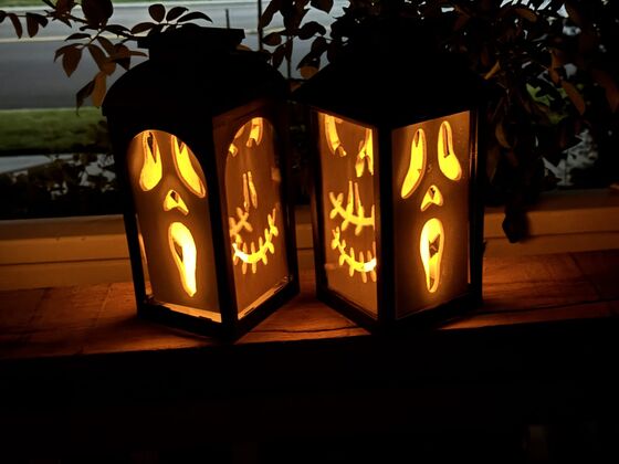 Dolly's Halloween lanterns — carved ghost, jack-o'-lantern, and bat designs glowing on a porch rail at night
